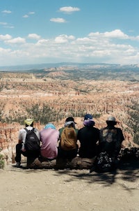 a group of people sitting on a log in bryce canyon national park