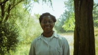 a woman in glasses standing in a wooded area