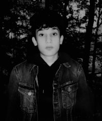 a black and white photo of a boy in the woods